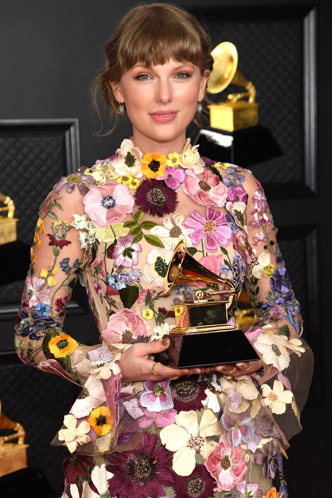 Taylor Swift holding a Grammy in floral dress