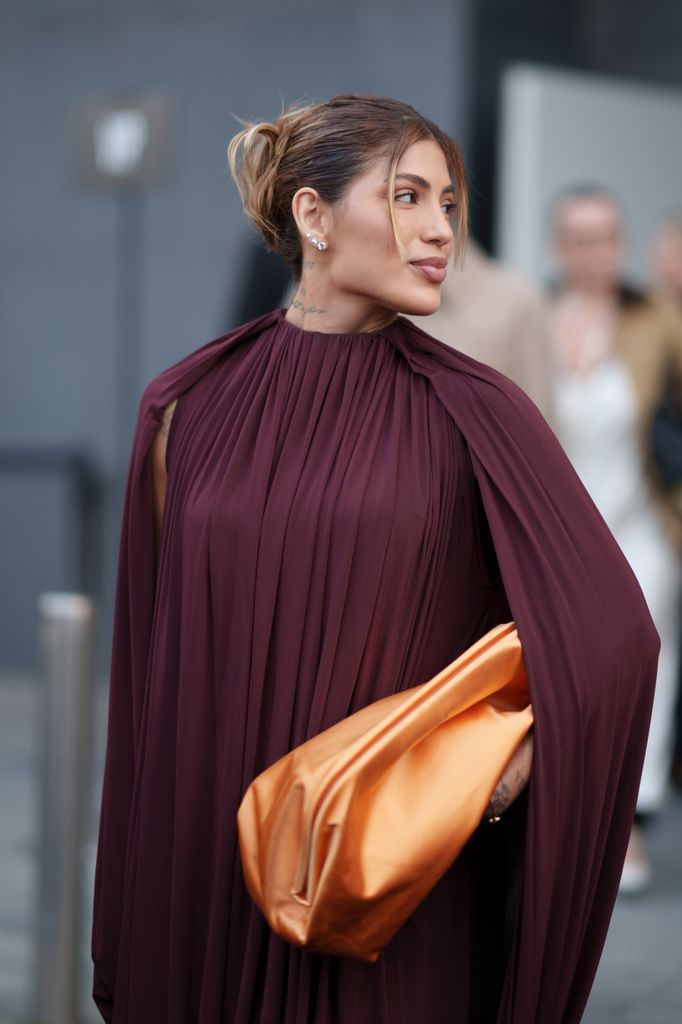 Um convidado usando um vestido maxi drapeado cor de vinho com mangas compridas é visto do lado de fora da Philosophy di Lorenzo Serafini durante a Milan Fashion Week Menswear Primavera/Verão 2025 em 19 de setembro de 2024 em Milão, Itália. 