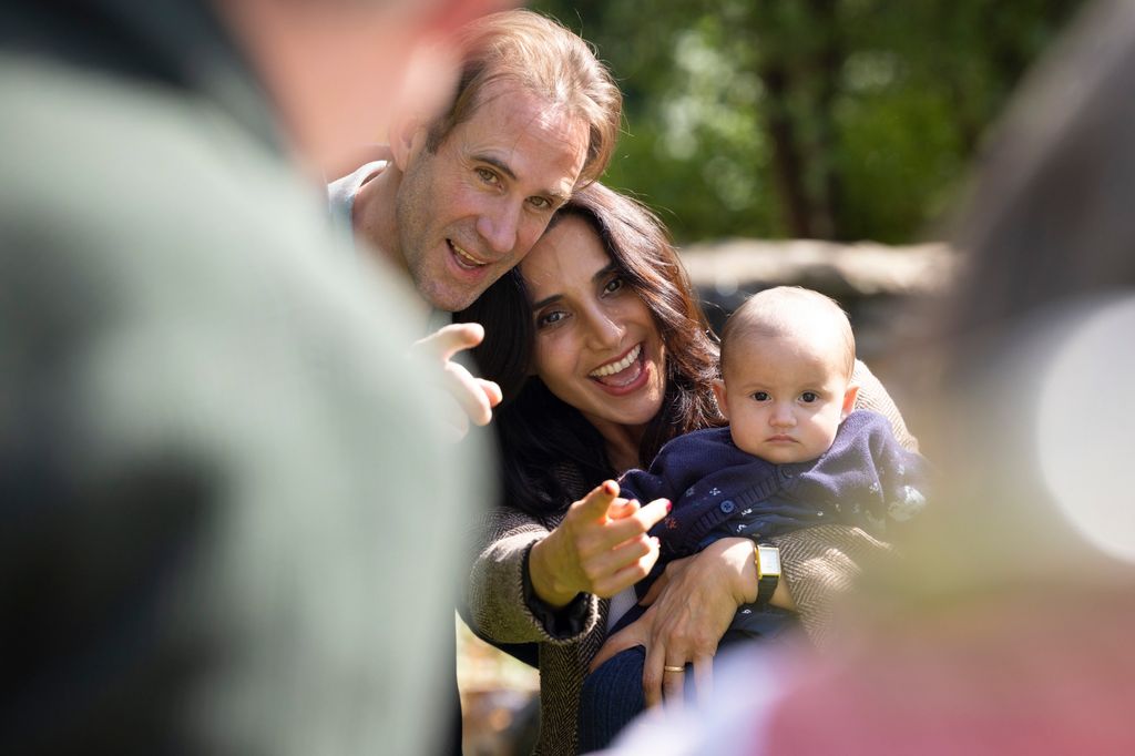 A. photo of two adults smiling while holding a baby