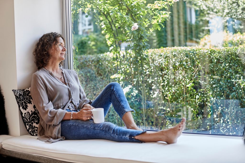  middle aged woman sitting on windowsill