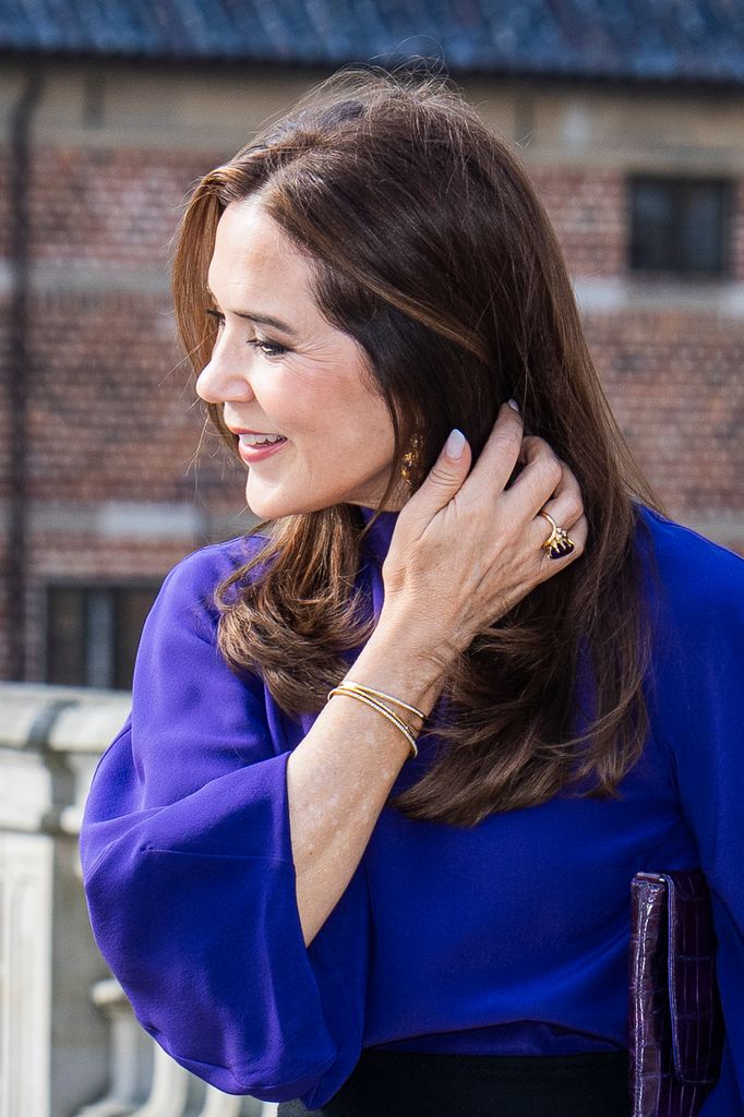 Queen Mary of Denmark tucking her dark hair behind her ear giving a glimpse of her earrings