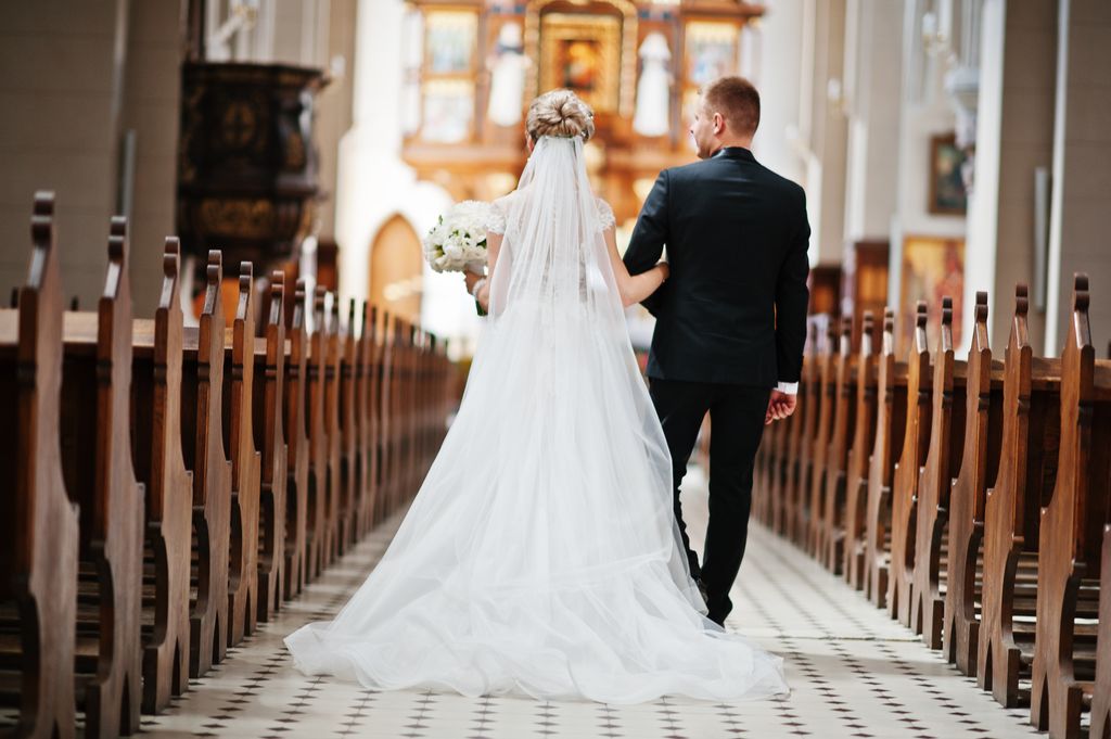 Bride with a long veil walking down the aisle in a church