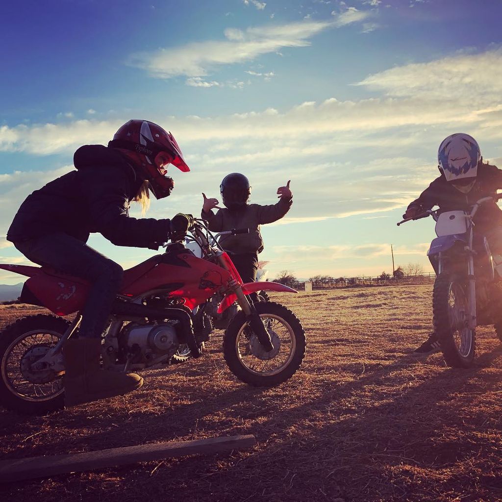 Three kids dirt biking with crash helmets on