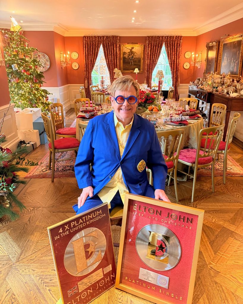 Elton John posing with his singles in his Windsor home