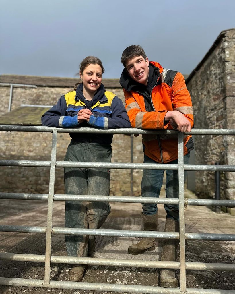 couple smiling and leaning on farm gate