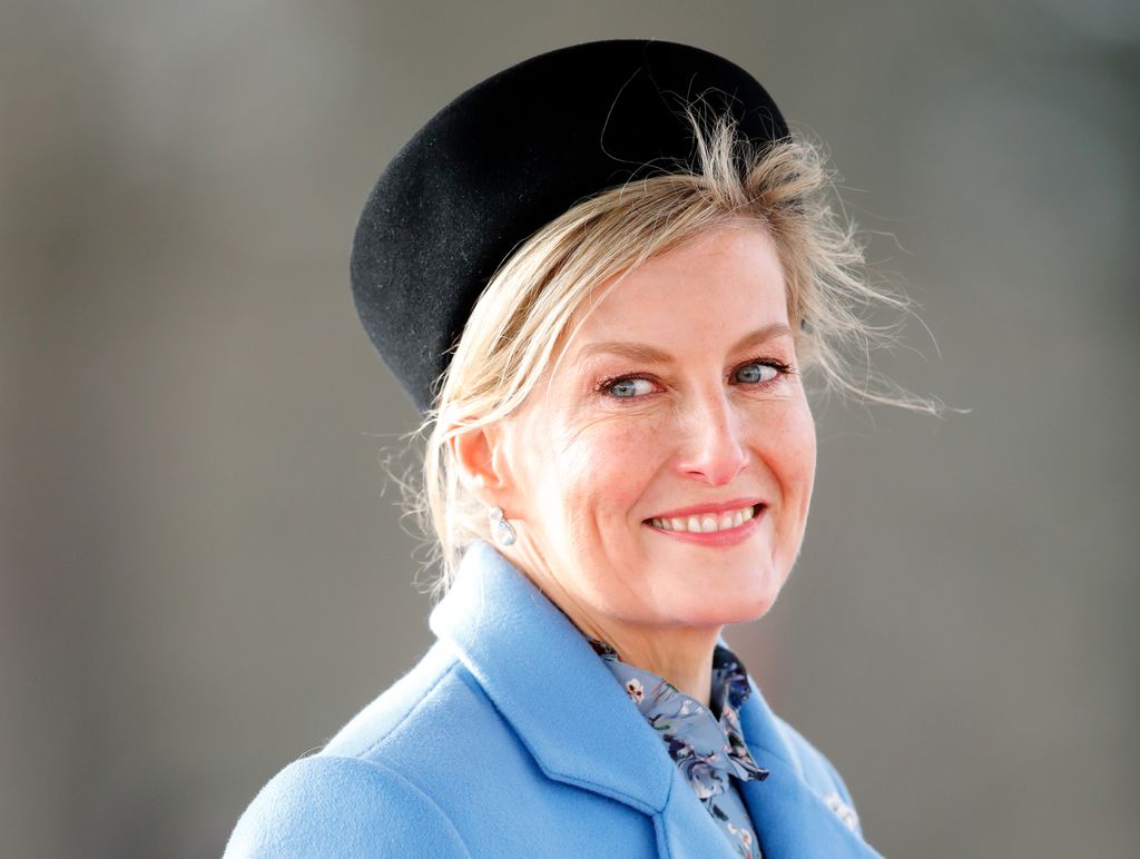 Sophie shoulders up in blue coat and black hat