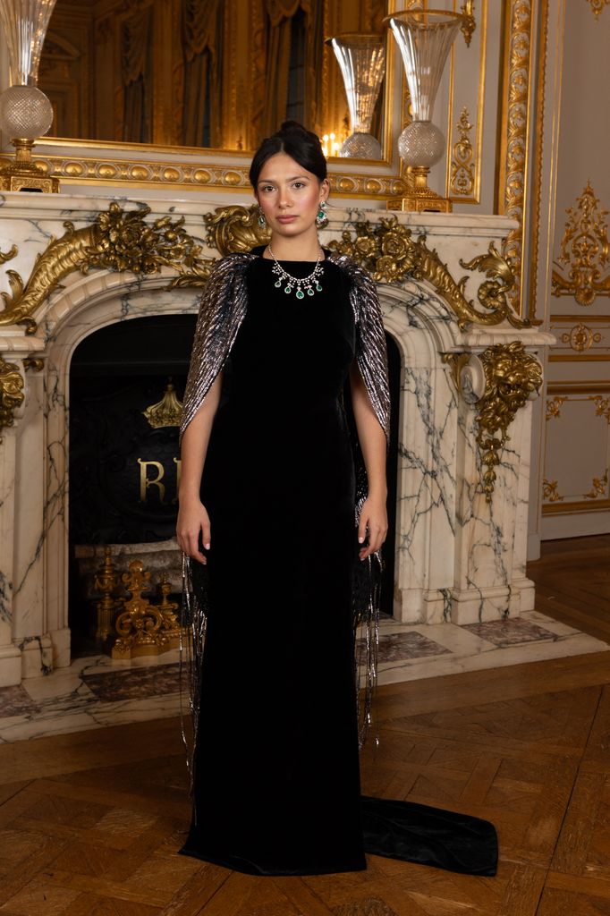Alexandra Moxey in caped navy gown in front of grand fire place
