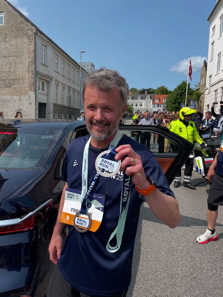 King Frederik holding up running medal