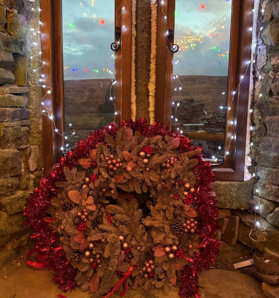 christmas wreath in window inside rustic property