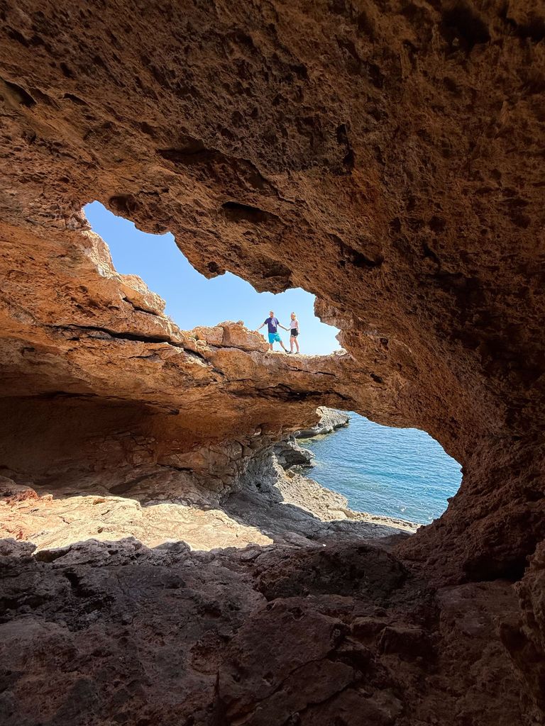 Two people hiking across a cave in Ibiza