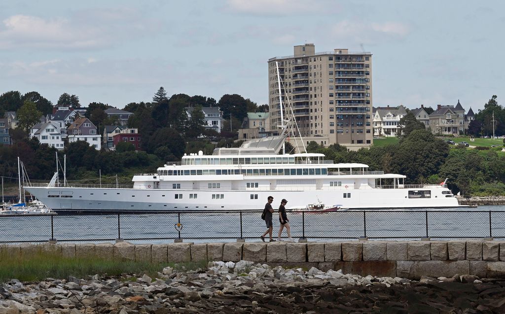 People walk at Bug Light Park in South Portland with The Rising Sun, a five-story, 82-room super yacht owned by billionaire David Geffen, docked in the background in Portland Tuesday, August 22, 2023