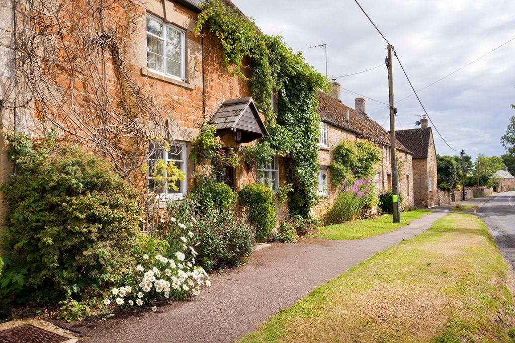 A row of 18th century  terraced cottages in the village of Kingham, built from local Cotswold stone, they glow a honey yellow in the afternoon sun.