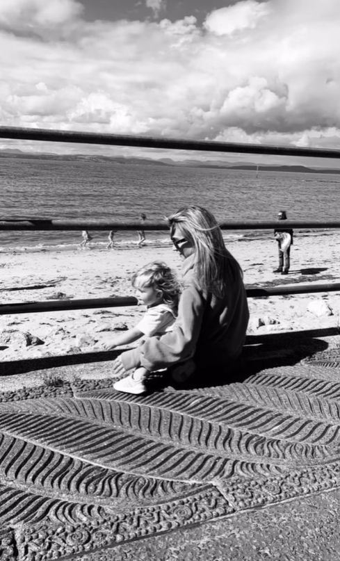 Helen Skelton and daughter sat on the edge of the beach