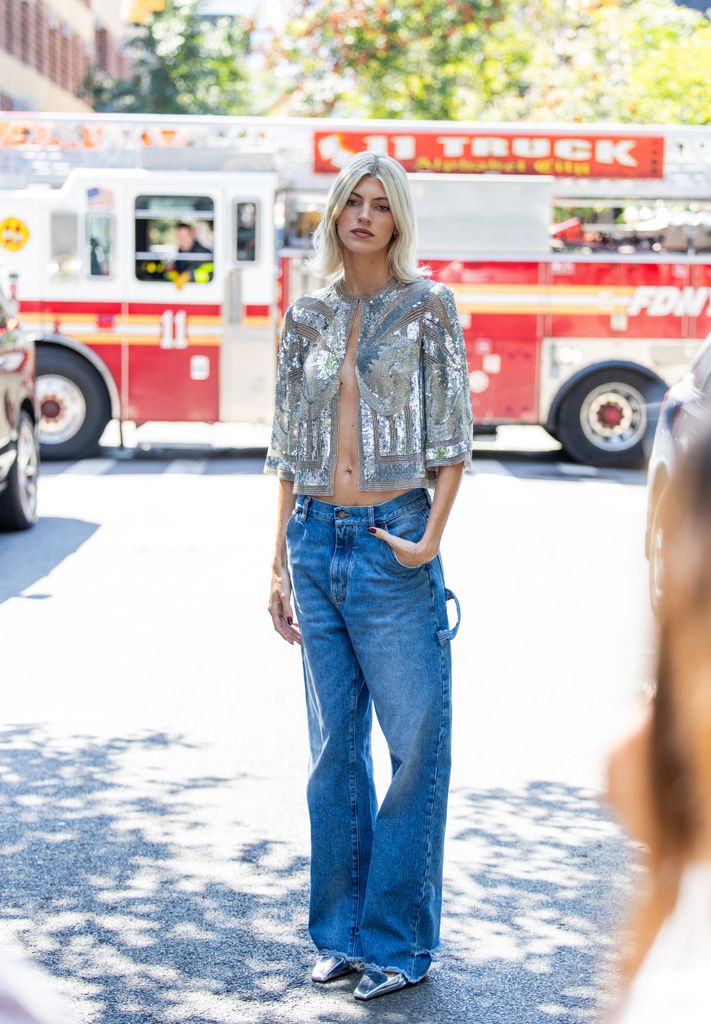 Devon Windsor wears sequined top, denim jeans outside Naeem Khan during New York Fashion Week on September 09, 2024 in New York City.