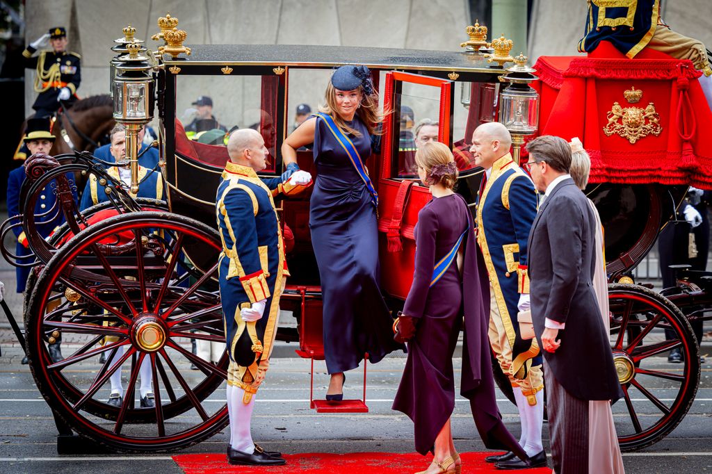 Princess Ariane being helped out of a carriage as Princess Alexia looks on