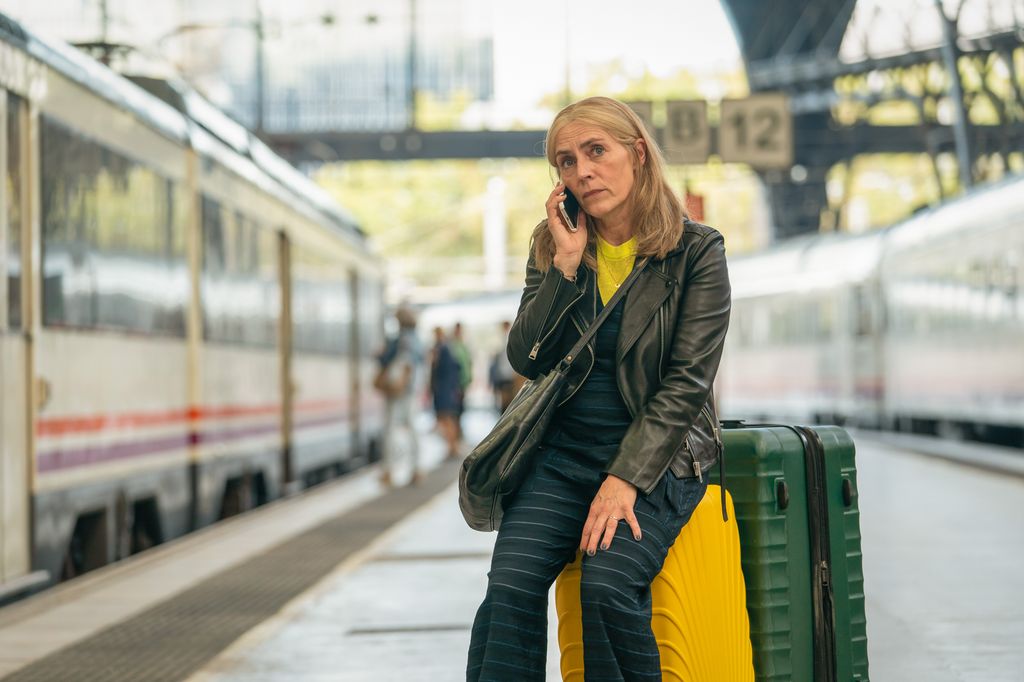 woman sitting on suitcase in train station