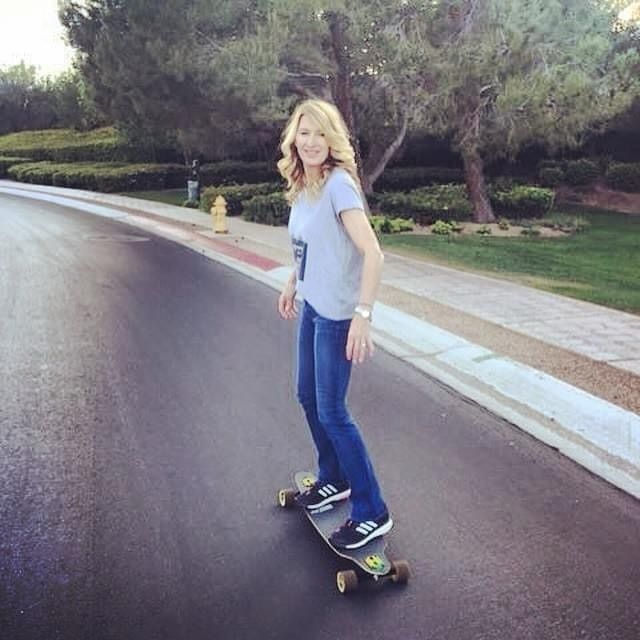 Stefi Graff in blue jeans and grey t-shirt riding a skateboard