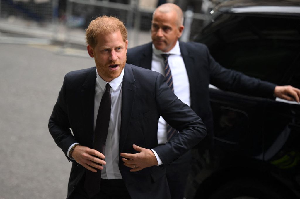 Prince Harry in a dark suit enters the court