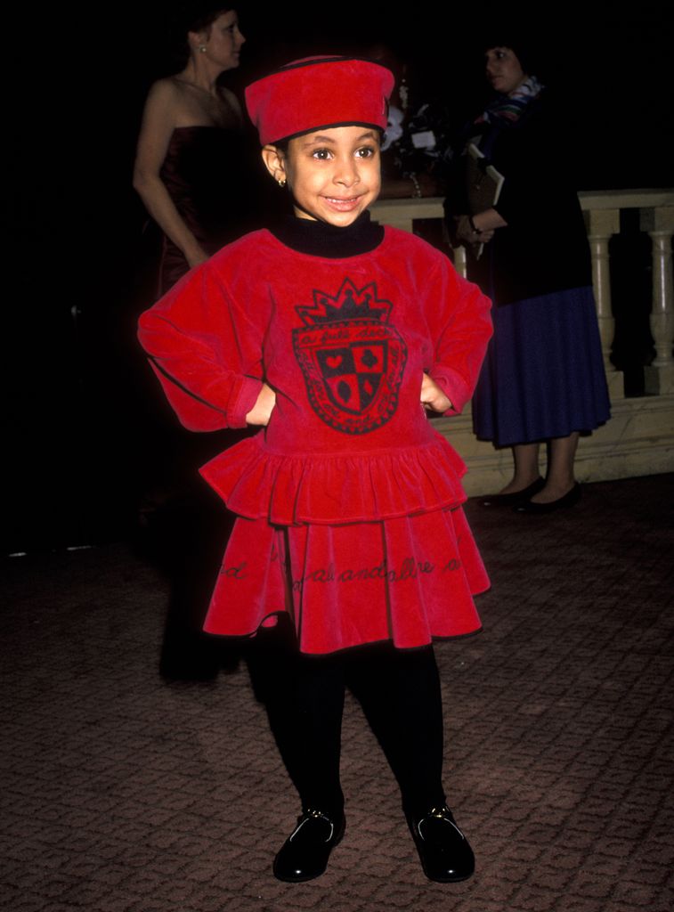 Raven Symone as a little girl in a red dress and red hat