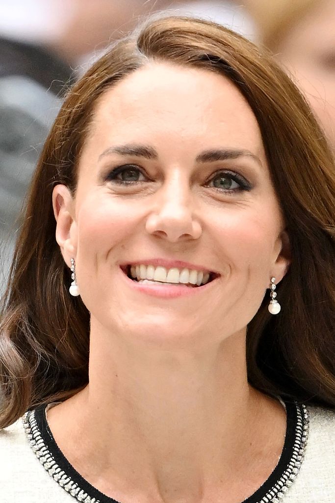 Princess Kate smiling in a close-up photo wearing a black and white jacket