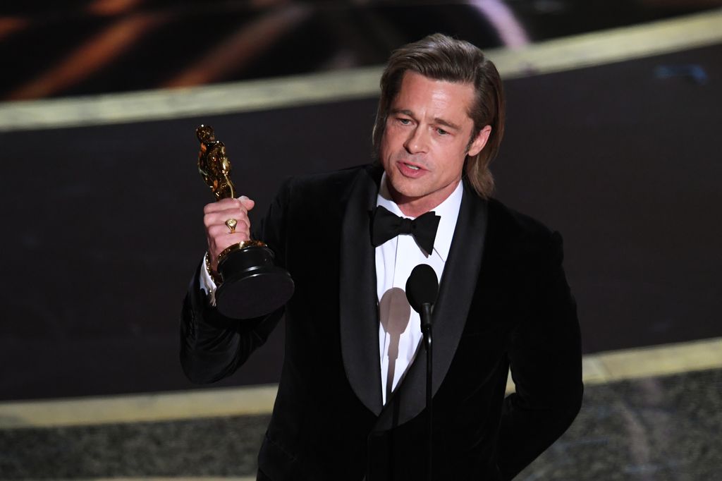 Brad Pitt holding his Oscar on stage at the Academy Awards making his speech 