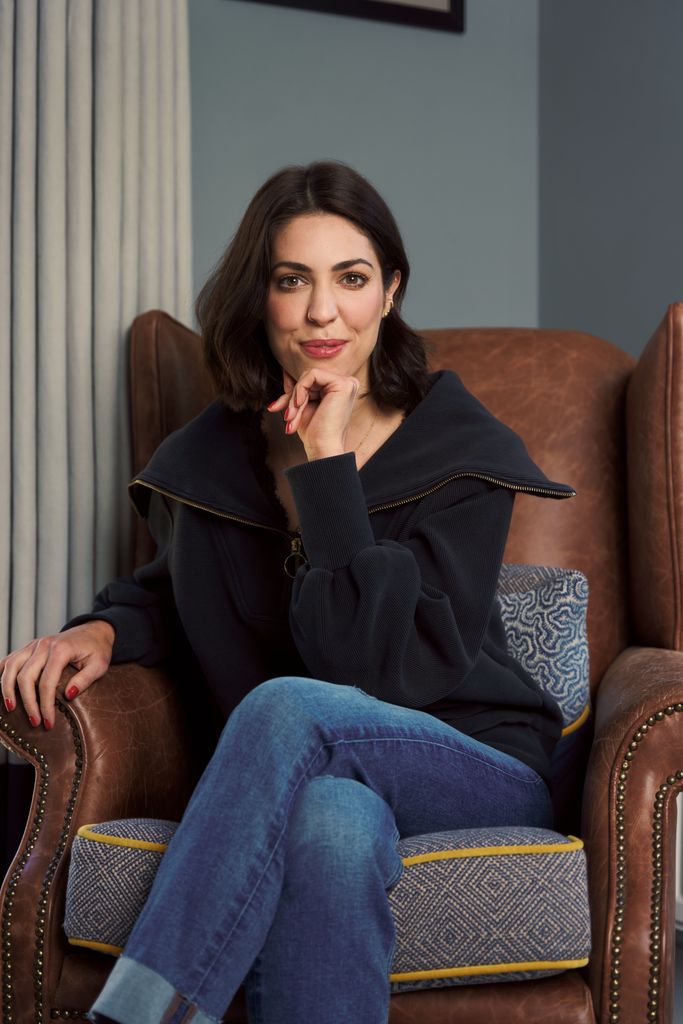 woman in jeans and a black top sitting in a comfy chair 