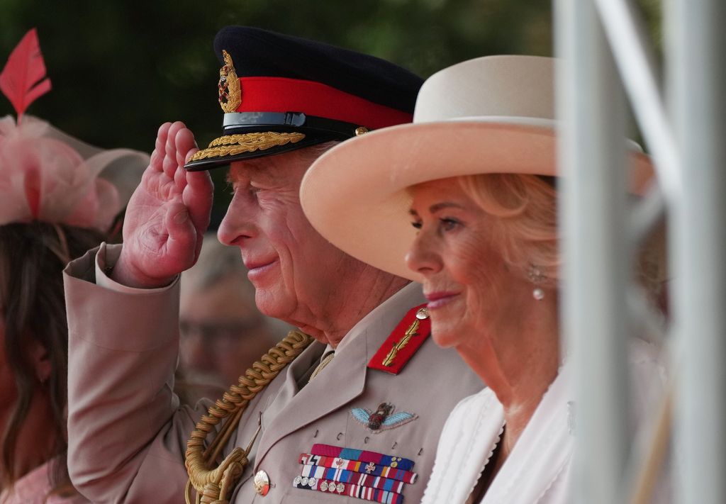 King Charles III salutes while sat next to Queen Camilla as they attend the Service of Remembrance 