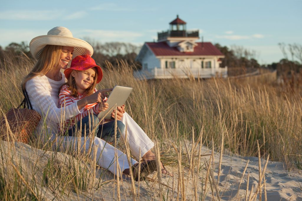 Caucasian mother and daughter using digital tablet on beach