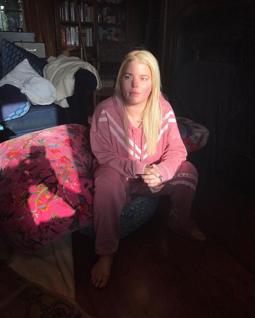 Jessica Simpson sits in a dimly lit room in a pink tracksuit, make up free 