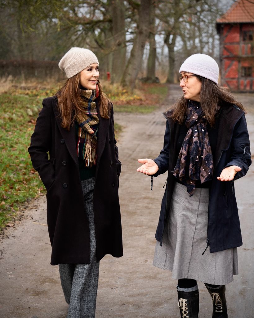 Queen Mary in a beanie and winter coat talking to woman