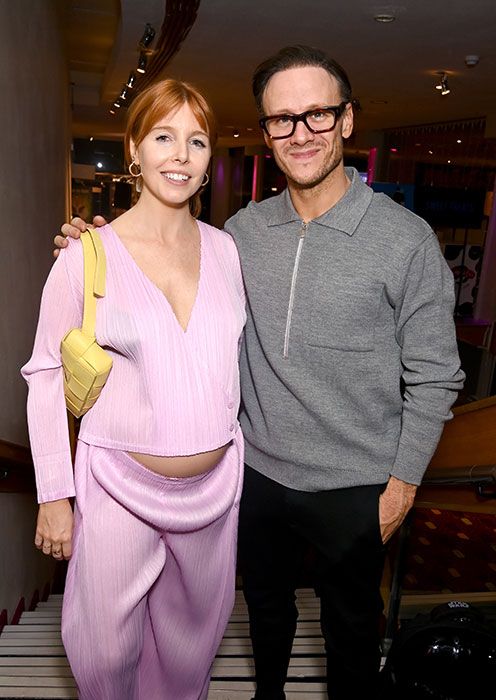 Pregnant Stacey Dooley in a pink outfit next to her partner Kevin