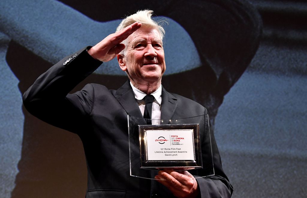 David Lynch saluting in a black suit