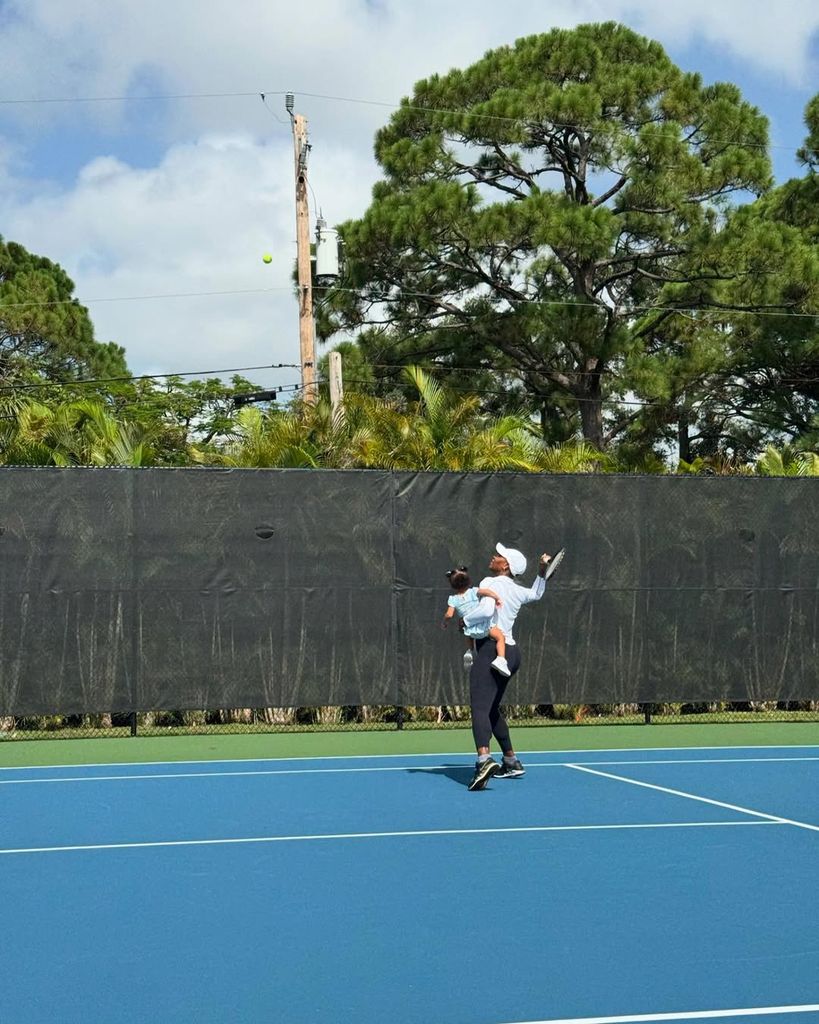 Serena holding her daughter mid serve