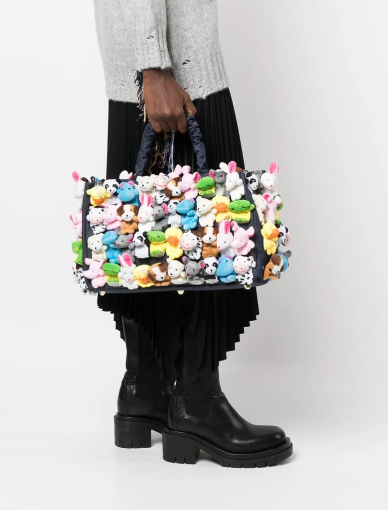 A picture of a model holding a handbag covered in colourful plushies