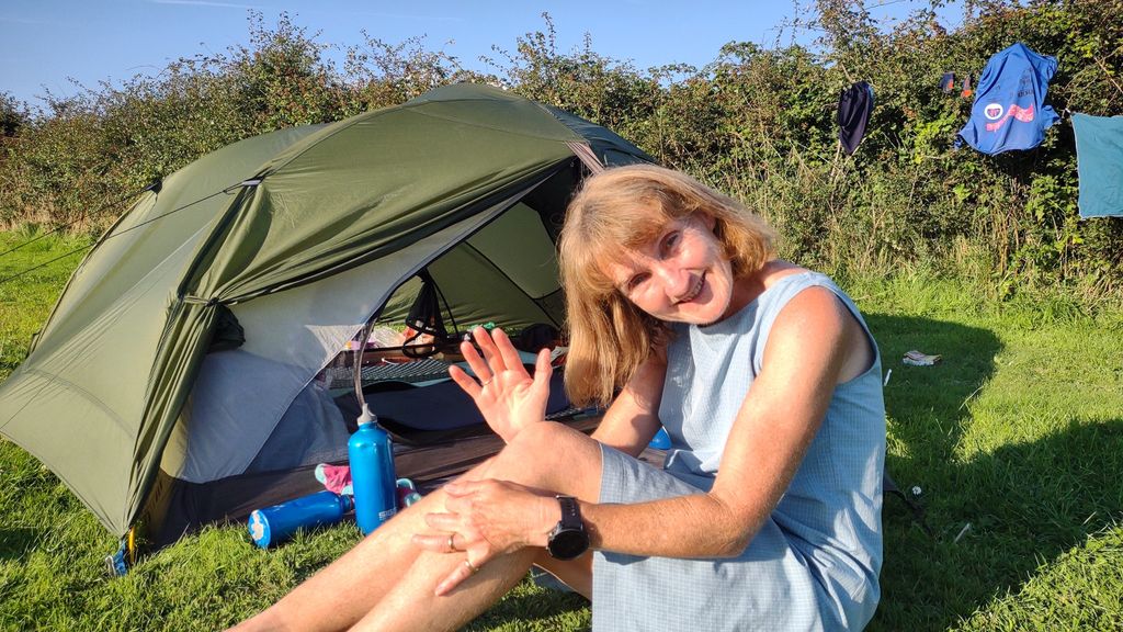 Woman waving in front of a tent 