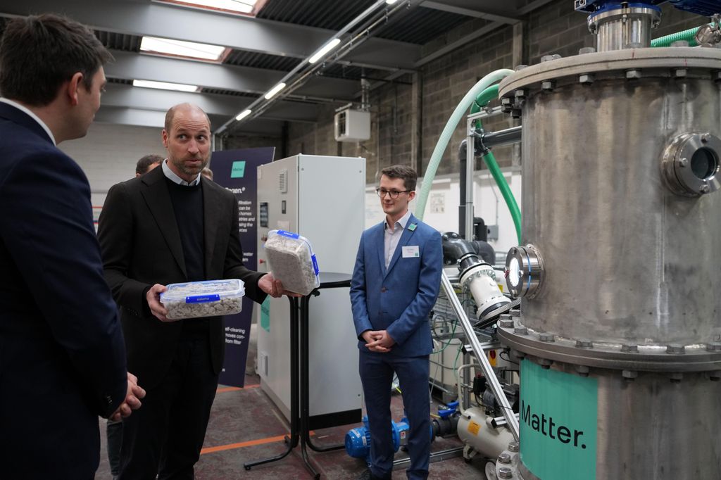 Prince William holding boxes of waste products as he stands with machines
