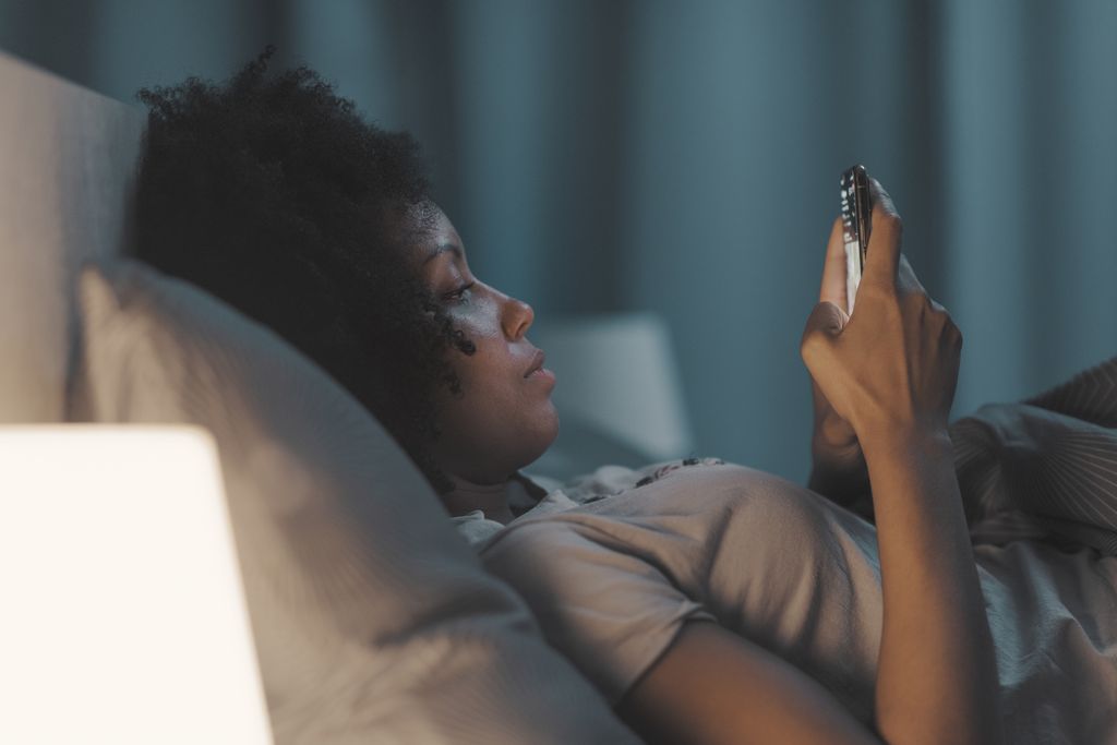 woman looking at her phone in bed at night