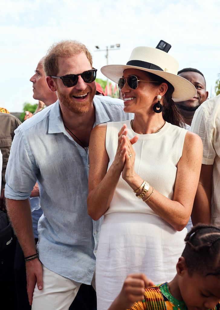 Príncipe Harry e Meghan usando óculos escuros e sorrindo na Colômbia