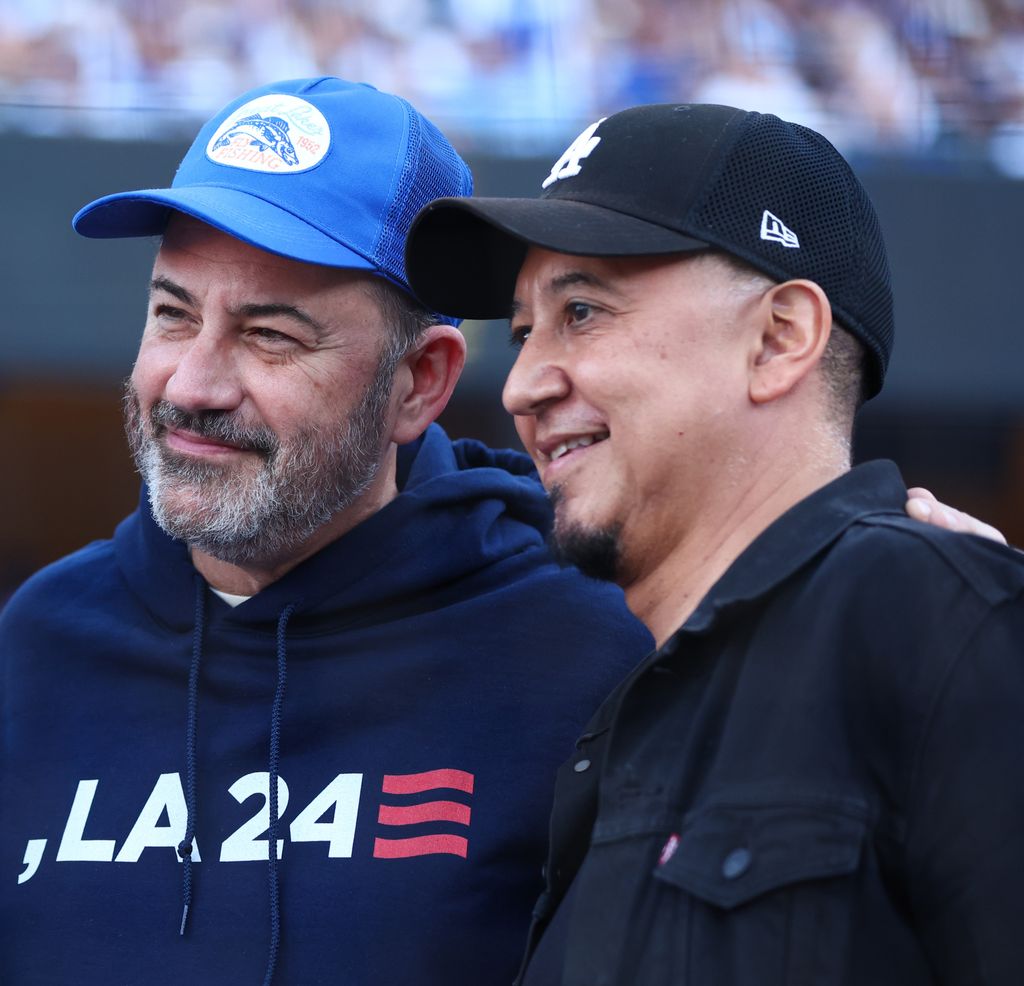 Cleto and Jimmy smile in baseball caps at a sporting event