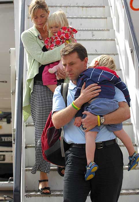 Kate and Gerry descending some plane steps with their twins in their arms