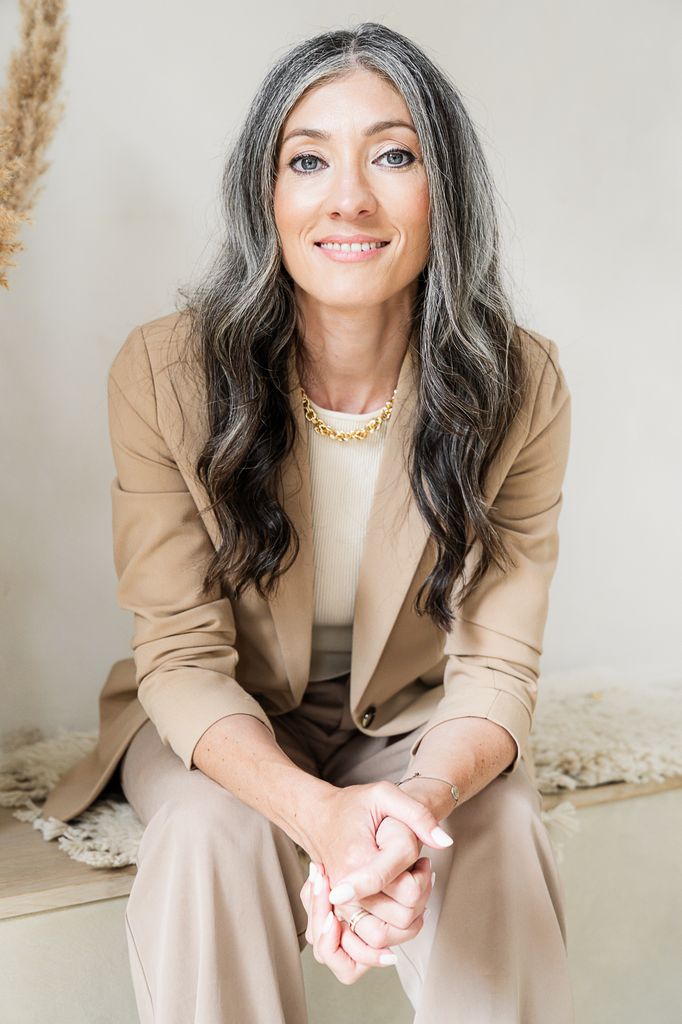 grey haired women smiling in a beige blazer 