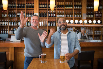 Happy friends watching football match while having beer in the restaurant