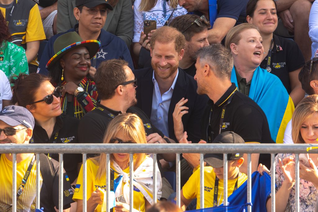 Gloria Orwoba and Prince Harry sitting in the stands 