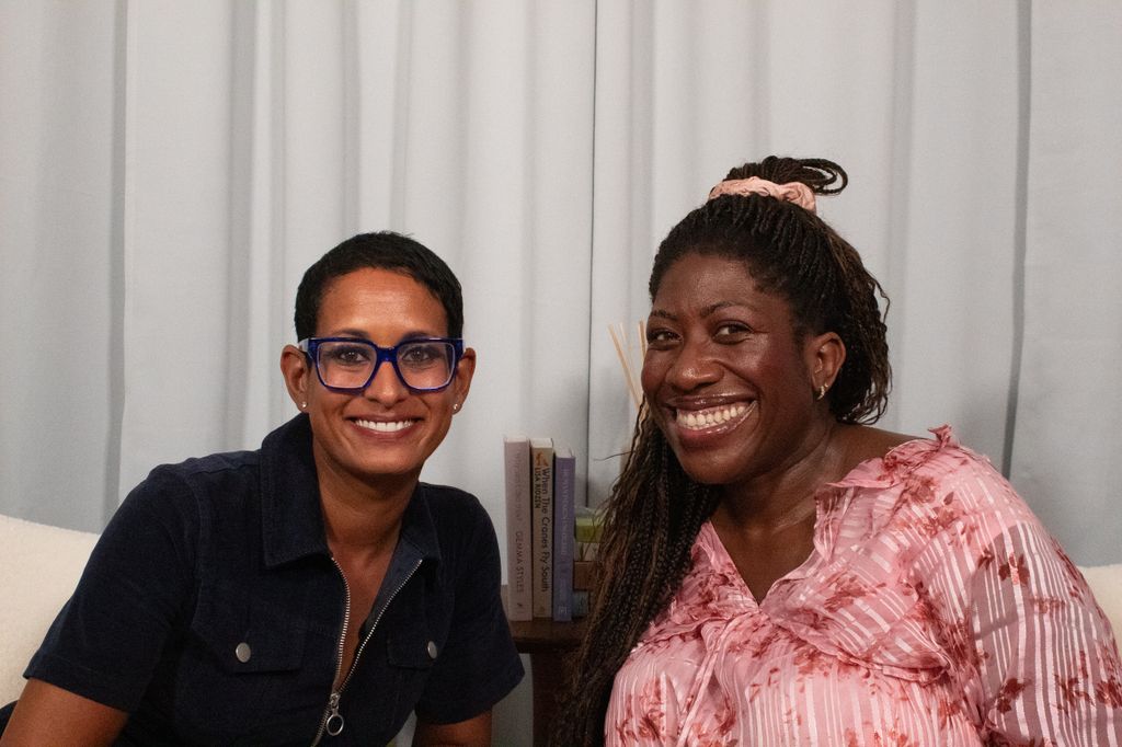 Two women smiling together in a podcast studio 