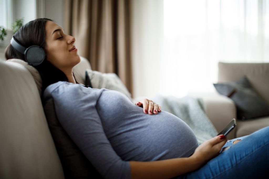 woman cradling bump listening to music