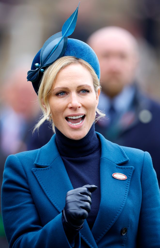 Zara Tindall smiling at Cheltenham Festival wearing a blue hat