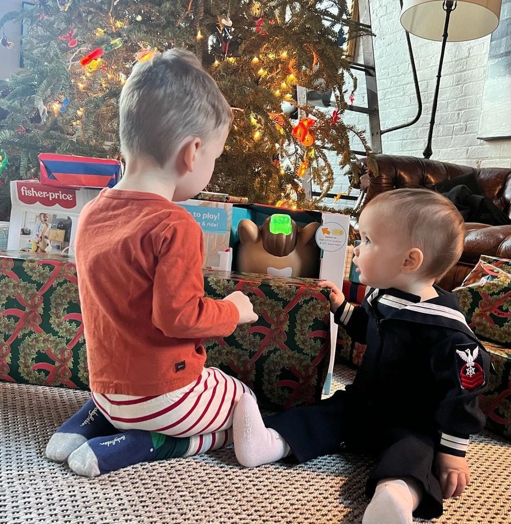 Wyatt and Sebastian sat at the foot of a Christmas tree along with several wrapped presents