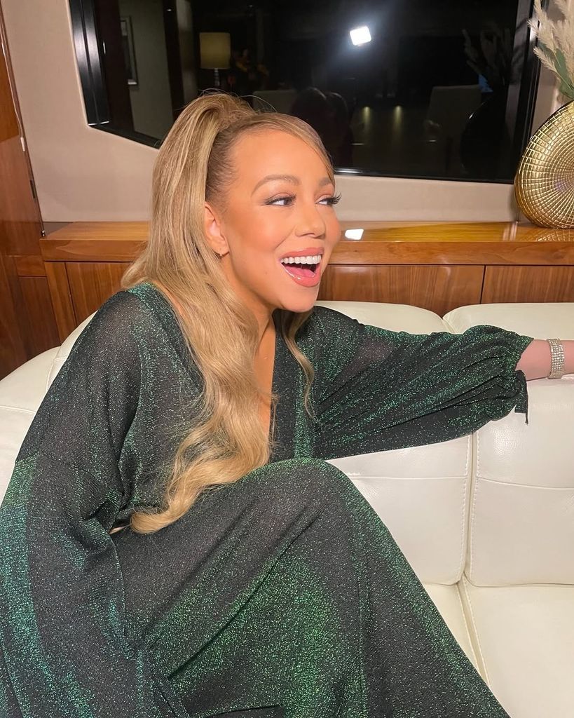 Mariah Carey smiling while wearing a green sparkly dress
