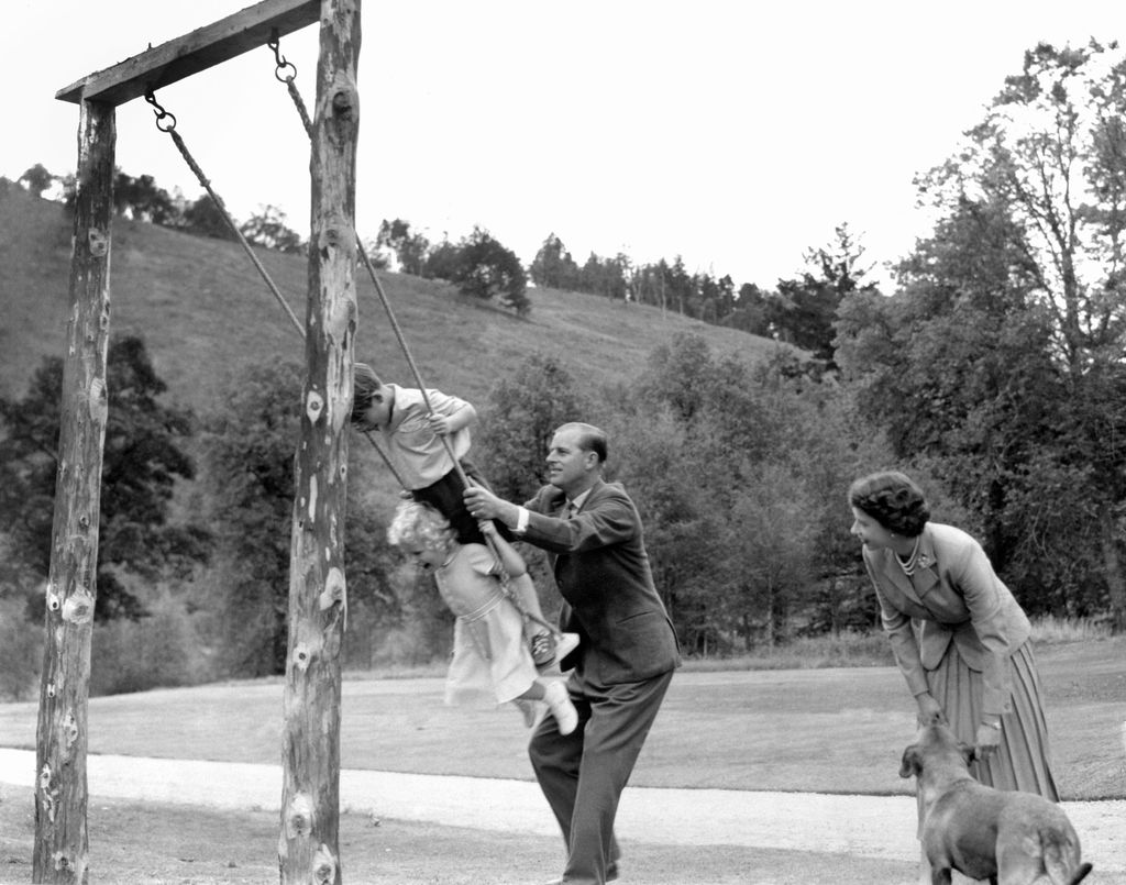 Prince Charles and Princess Anne being pushed on a swing by their father, the Duke of Edinburgh, with their mother Queen Elizabeth II looking on, in the grounds of Balmoral. 