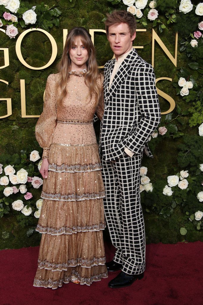 Eddie Redmayne in a black and white suit and Hannah Bagshawe in a tiered dress